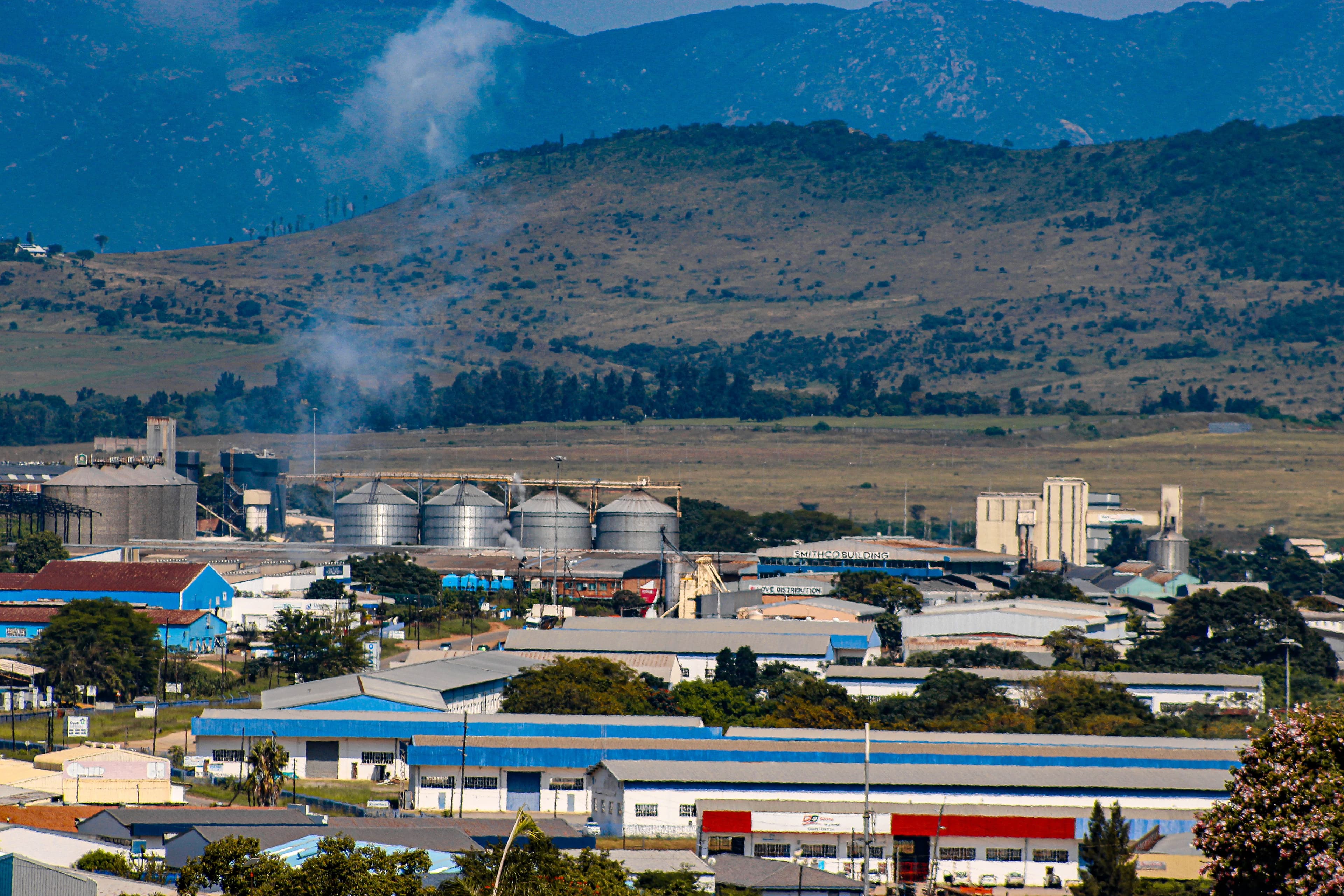 Industrial facilities and storage silos set against a mountain backdrop