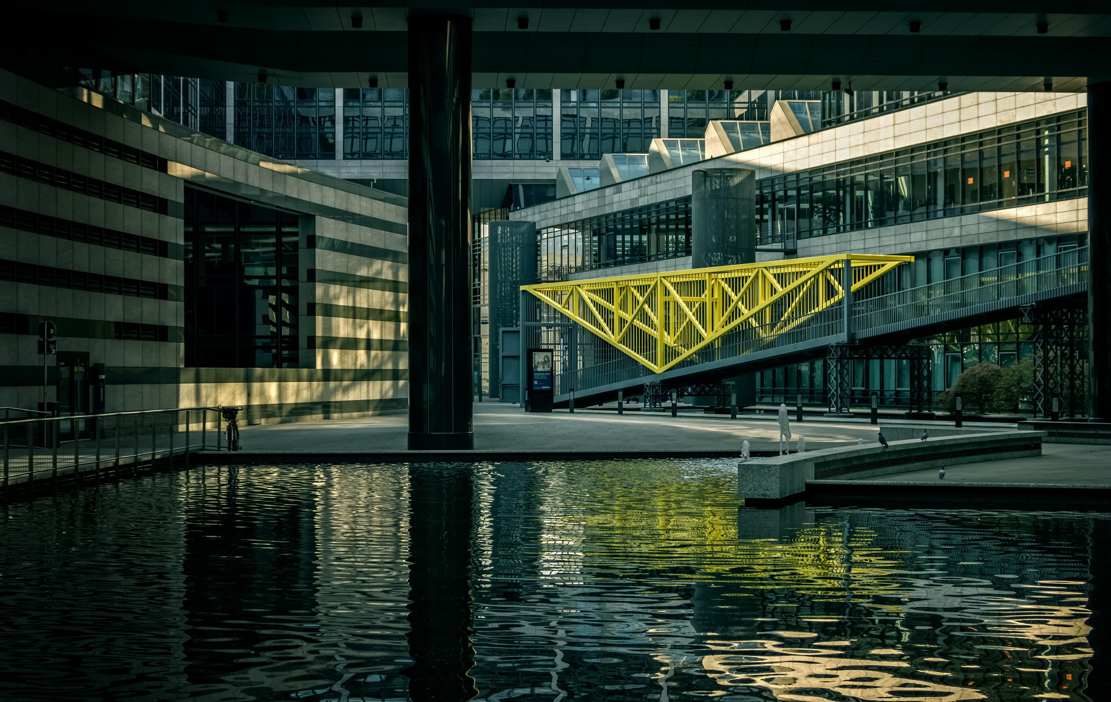 A modern pedestrian bridge connecting institutional office buildings over water