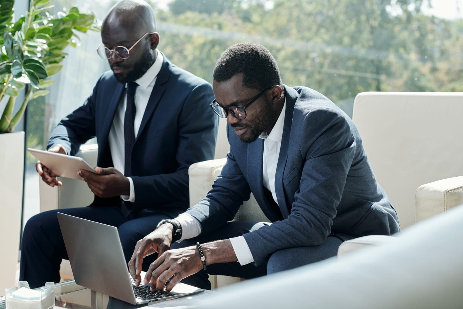 Two advisors reviewing project documents together on a laptop and tablet